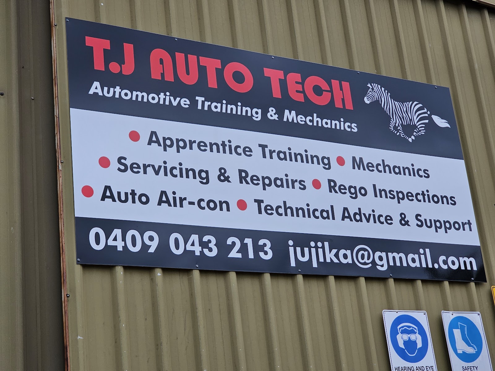 The TJ Auto Tech sign on the shed wall, listing services, phone number and email