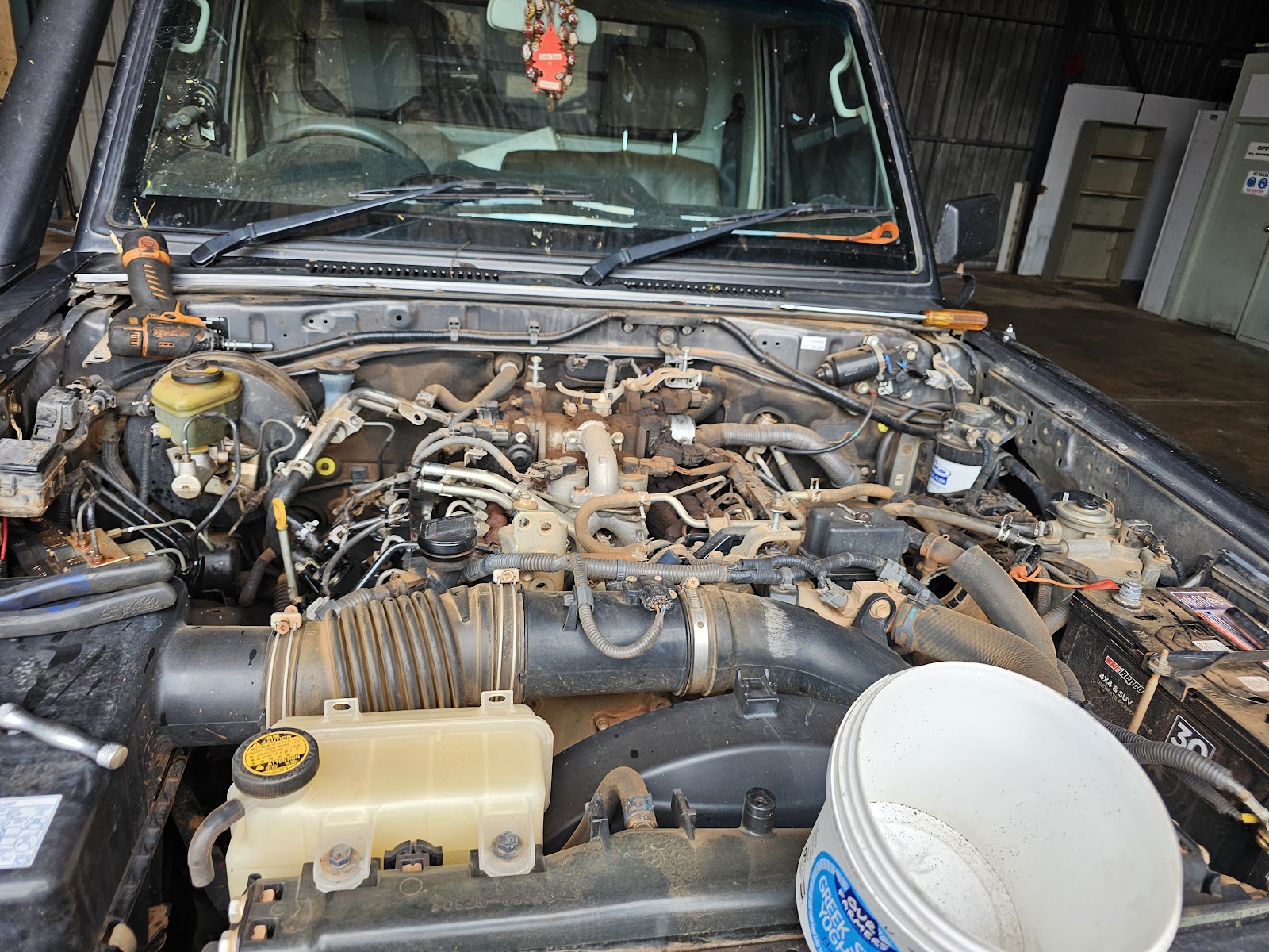 Engine bay of a LandCruiser mid-job at TJ Auto Tech, tools resting on the cowl
